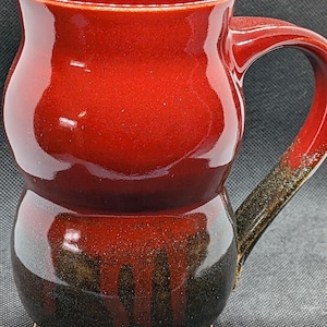 May include: A white ceramic mug with a black handle and the text "But First, Coffee" in a handwritten style. The mug is on a white surface. The mug is approximately 4 inches tall.