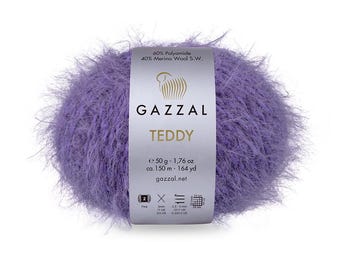 Puede incluir: Un ovillo de hilo morado y peludo llamado Gazzal Teddy. El hilo es 60% poliamida y 40% lana merino. El ovillo pesa 50 gramos y tiene 150 metros de largo.