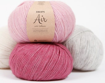 May include: Three balls of yarn in pink, light pink, and white. The pink ball has a label that reads "DROPS Air uni colour" and "Find free knitting & crochet patterns at garnstudio.com".