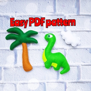 May include: Easy PDF pattern for a green felt dinosaur and a green felt palm tree with a brown trunk. The dinosaur has a yellow belly and a white cloud is behind it.
