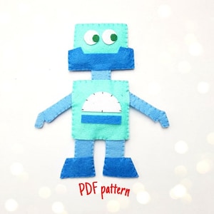 May include: A blue felt robot with green eyes, a white dial, and the text "PDF pattern".