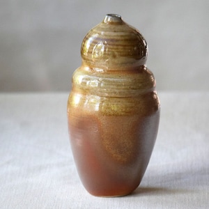 Soda fired handthrown ceramic pottery bottle or vase altered in a wavy shape. Glazed in tones of rust, blue green and yellow salt