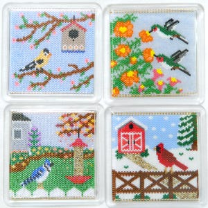 Puede incluir: Juego de cuatro posavasos cuadrados con diseños detallados de cuentas. Cada posavasos presenta una escena natural diferente: una casa para pájaros, colibríes, un arrendajo azul y un cardenal. Los posavasos tienen bordes de plástico transparente.