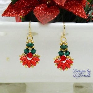 May include: A pair of dangle earrings featuring gold-tone hooks, small gold beads, faceted dark green crystals, and a fan-shaped arrangement of bright red oval beads. The text Design by LJSmith is printed in blue in the lower right corner.