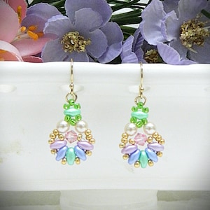 May include: A pair of drop earrings featuring gold-tone hooks and a circular arrangement of beads. The design includes small lime green, white pearl-like, metallic gold, light pink crystal, lavender, and mint blue beads in a symmetrical pattern.