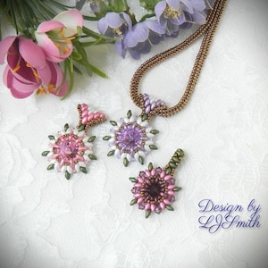 May include: Three beaded flower pendants in shades of pink, purple, and white. One pendant is attached to a beaded necklace. The design includes green accents. The text "Design by L.J. Smith" is in the lower right corner.