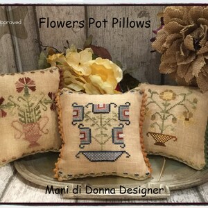 Può includere: Tre fodere per cuscini ricamate con motivi floreali. I cuscini sono beige con accenti marroni, verdi e rossi. I cuscini sono etichettati "Flowers Pot Pillows" e "Mani di Donna Designer".