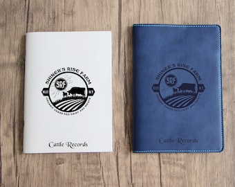 Puede incluir: Dos cuadernos blancos y azules con el logotipo "Shingr's Rise Farm" y el texto "Cattle Records".