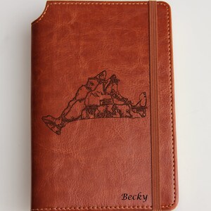 Könnte beinhalten: Ein braunes Lederjournal mit einer eingravierten Karte von Long Island, New York, auf der Vorderseite. Der Name "Becky" ist unten auf dem Journal eingraviert.