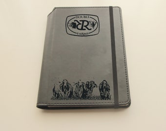 May include: Gray leather-bound journal with a black elastic closure. The front cover features an engraved logo with the text "DOUBLE R FARMS" and a silhouette of cattle.