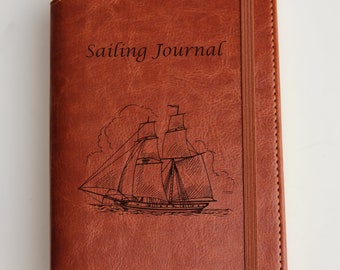 May include: A brown leather-bound journal with a sailing ship and the text "Sailing Journal" engraved on the front. The name "Clare Masley" is also engraved on the front.
