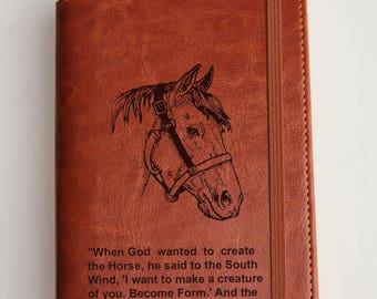 Può includere: Un diario in pelle marrone con un'illustrazione di un cavallo e una citazione di Emir Abd-el-Kader: "Quando Dio volle creare il Cavallo, disse al Vento del Sud, 'Voglio fare una creatura di te. Diventa Forma.' E il Vento divenne Forma."