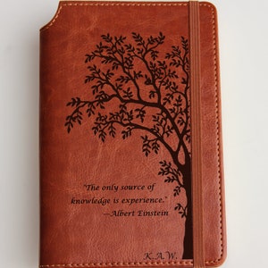 May include: Brown leather journal with a tree design and the quote "The only source of knowledge is experience." - Albert Einstein. The journal also has the initials K.A.W. engraved on the front.