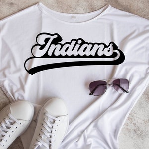 May include: White t-shirt with a black and white graphic that says "Indians" in a retro font.
