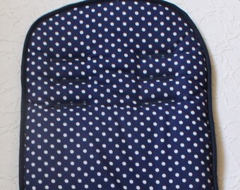 May include: A navy blue stroller seat liner with a white polka dot pattern. The liner has a padded headrest and two straps for securing it to the stroller.
