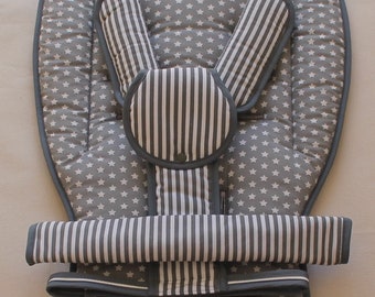 Könnte beinhalten: Ein grauer und weißer Kinderwagen-Sitzbezug mit Sternenmuster und einem gestreiften Gurt. Der Bezug hat eine gepolsterte Kopfstütze und einen Riemen, um ihn am Kinderwagen zu befestigen.