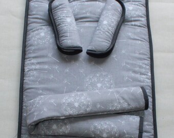 Könnte beinhalten: Ein grauer Kinderwagen-Sitzbezug mit einem weißen Löwenzahnmuster. Der Bezug hat zwei graue gepolsterte Gurte mit schwarzem Besatz.