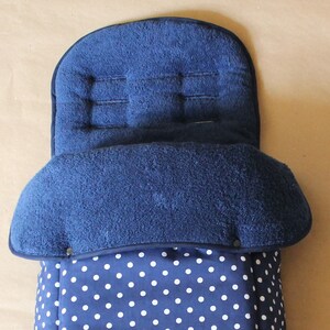 Op de afbeelding: Een blauwe en witte stippen kinderwagen voetenzak met een fleece voering. De voetenzak is ontworpen om een baby warm en comfortabel te houden in een kinderwagen.