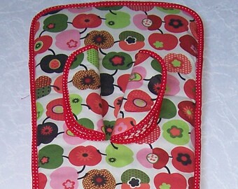 Könnte beinhalten: Ein Ofenhandschuh mit einem farbenfrohen Blumenmuster mit roten, rosa, grünen und schwarzen Blumen auf weißem Grund. Der Handschuh ist mit einem roten Pünktchenmuster eingefasst.