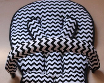 Könnte beinhalten: Schwarzer und weißer Baby-Kinderwagen-Sitzbezug mit Chevron-Muster, gepolsterter Kopfstütze und Armlehnen.