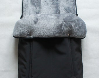 May include: Black stroller footmuff with a gray fleece lining. The footmuff has a zipper closure and a flap that can be folded down.