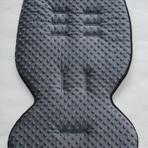 Könnte beinhalten: Grauer Baby-Autositz-Einsatz mit strukturierter Oberfläche und schwarzem Besatz. Der Einsatz hat einen erhöhten Mittelteil und zwei seitliche Flügel.