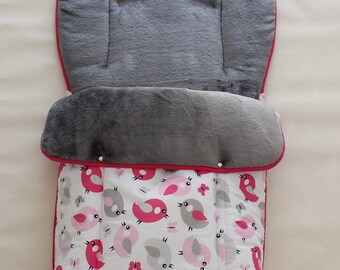 May include: A pink and gray stroller liner with a pattern of pink and gray birds and butterflies. The liner has a gray fleece lining and a pink trim.