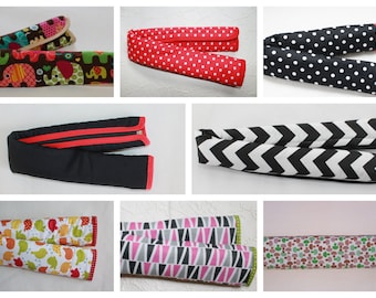 May include: A set of 10 colorful fabric car seat belt covers. The covers are made of different fabrics with various patterns, including elephants, polka dots, zigzags, and geometric shapes. The covers are designed to protect car seats from wear and tear.