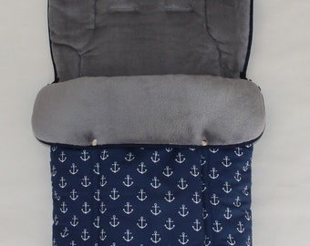 May include: A blue stroller footmuff with a white anchor pattern. The footmuff has a gray fleece lining.
