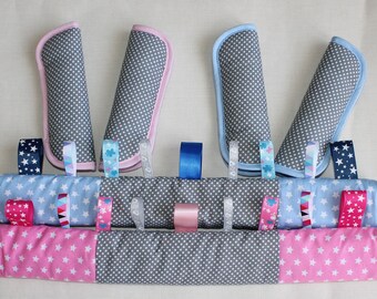 May include: A gray and white polka dot baby activity toy with pink, blue, and white ribbons. The toy has two gray and white polka dot fabric loops on each end.
