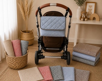 May include: A baby stroller with a blue and white checkered diaper bag. Rolled and folded blankets in beige, red, black, and blue checkered patterns are displayed. A wicker basket holds rolled blankets. A stack of blankets is on the floor.