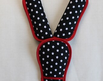 May include: A set of three black and white star patterned seatbelt shoulder pads with red trim.