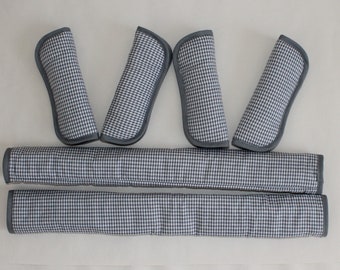 May include: Set of seven black and white checkered seat belt pads. The pads are designed to protect your shoulders and neck from chafing and discomfort.