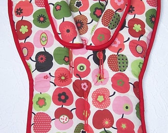 May include: Red and green patterned baby seat cushion with a red trim. The cushion has a white background with a repeating pattern of red apples with green leaves and white flowers.
