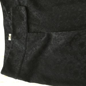 Puede incluir: Falda negra con estampado floral. La falda tiene cintura alta y corte recto.