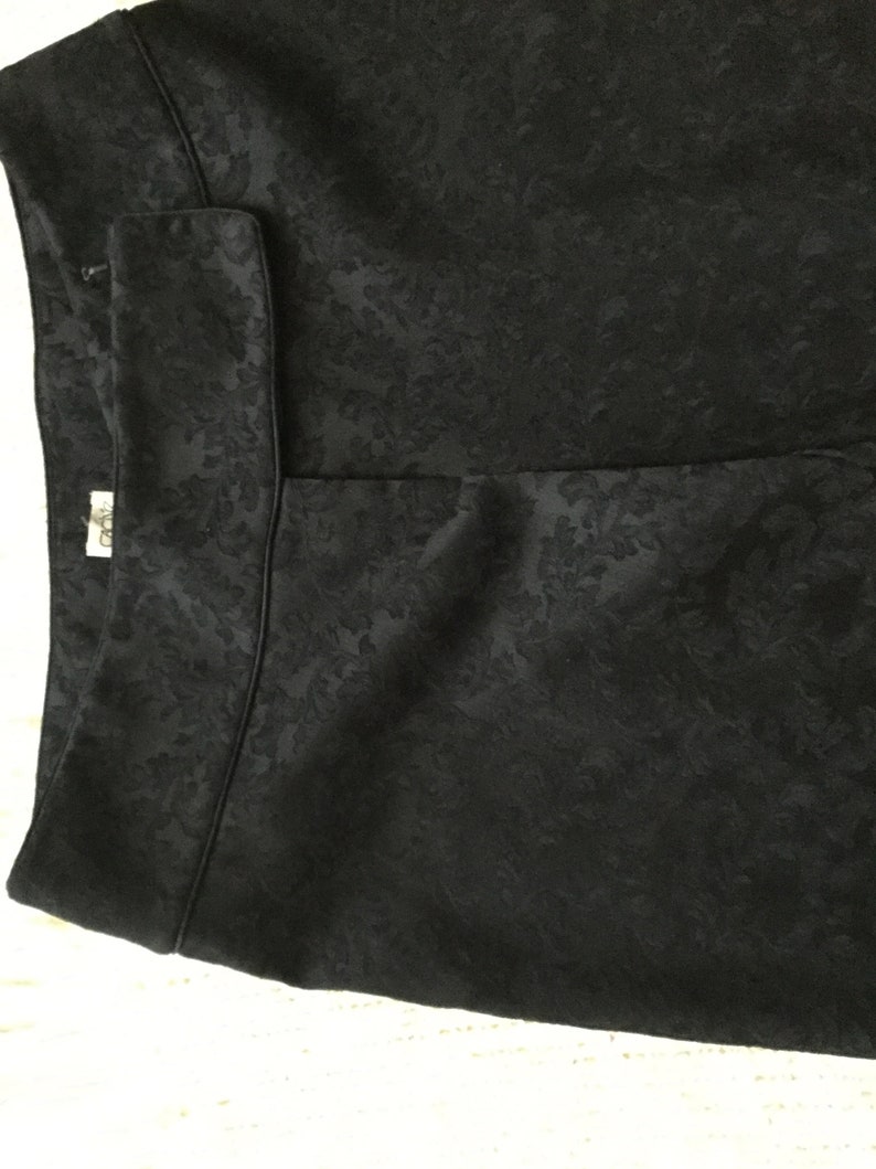 Puede incluir: Falda negra con estampado floral. La falda tiene cintura alta y corte recto.