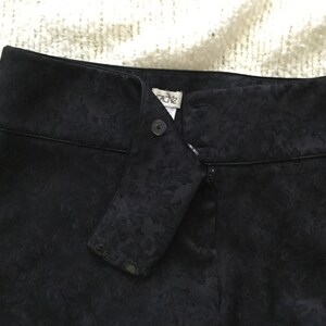 Puede incluir: Pantal&oacute;n negro con estampado floral y cierre de cremallera y bot&oacute;n. El pantal&oacute;n tiene una etiqueta que dice "Cache".