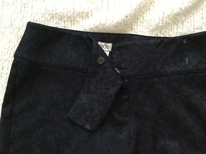 Puede incluir: Pantal&oacute;n negro con estampado floral y cierre de cremallera y bot&oacute;n. El pantal&oacute;n tiene una etiqueta que dice "Cache".