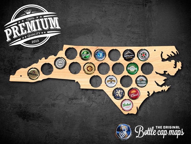 Op de afbeelding: Een houten flesdopkaart van North Carolina, met een bruine beitsafwerking. De kaart heeft 25 flesdop-slots. De kaart is gemonteerd op een zwarte muur. De tekst "The Original Bottle cap maps" is onder de kaart gedrukt.