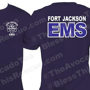 May include: A navy blue t-shirt with a white graphic of a medical symbol and the text "FORT JACKSON EMS" on the front and back. The shirt has a small American flag on the left sleeve.