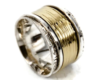 Puede incluir: Un anillo giratorio de plata y oro con una banda de oro texturizada y una banda de plata con un diseño grabado.