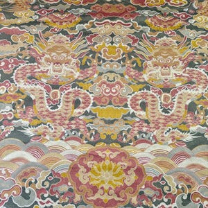May include: A detailed textile pattern featuring two stylized dragons facing each other. The design incorporates clouds, waves, and floral elements in shades of red, yellow, gray, and gold against a dark background. The overall aesthetic suggests an Asian-inspired theme.