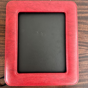 Peut inclure: Un cadre photo rectangulaire rouge avec un intérieur noir. Le cadre a une texture cousue semblable au cuir. Le cadre est conçu pour contenir une photographie ou une œuvre d'art. Le cadre est de conception classique.