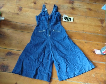 Könnte beinhalten: Ein blauer Jeans-Overall mit V-Ausschnitt und Reißverschluss vorne. Der Overall hat weite Beine und Taschen an den Seiten.
