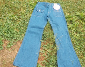 Könnte beinhalten: Blaue Schlaghose aus Denim mit Front- und Gesäßtaschen. Die Jeans hat eine hohe Taille und ein ausgestelltes Bein. Ein weißes Etikett ist hinten angebracht. Die Jeans liegt auf einer grünen Wiese.
