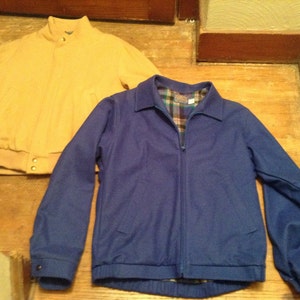 May include: Two jackets, one mustard yellow and one royal blue, both with a zipper closure. The blue jacket has a plaid lining visible at the collar.