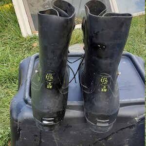 Op de afbeelding: Een paar zwarte rubberen laarzen met een vetersluiting. De laarzen hebben een maatlabel met de tekst "US 7-80 5 WX".