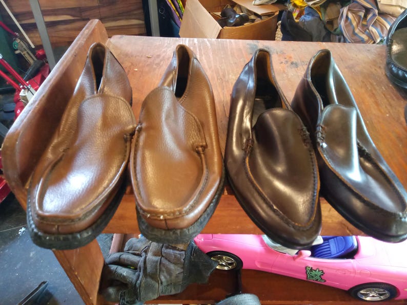 May include: Three pairs of leather slip-on shoes. Two pairs are brown and one pair is dark brown.