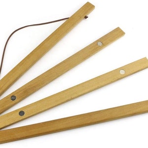 Pu&ograve; includere: Un set di quattro appendini per poster in legno con magneti. Gli appendini sono collegati da un cordoncino marrone e possono essere utilizzati per esporre poster o opere d'arte.