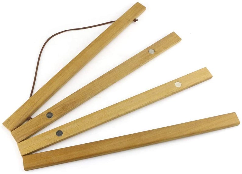 Pu&ograve; includere: Un set di quattro appendini per poster in legno con magneti. Gli appendini sono collegati da un cordoncino marrone e possono essere utilizzati per esporre poster o opere d'arte.